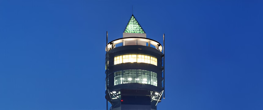 Верхня частина освітленої вежі на тлі темно-синього вечірнього неба.