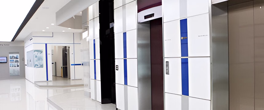 Світлий коридор з кількома ліфтами, оздобленими білими та синіми смугами, та глянцевою підлогою.