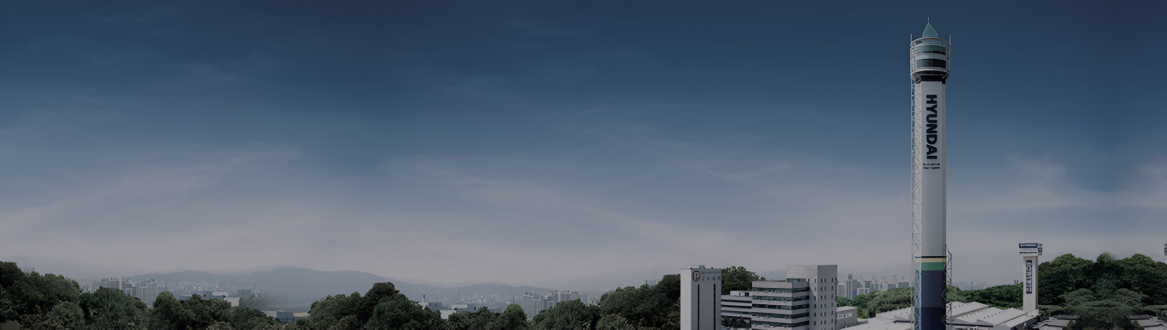 Випробувальна вежа ліфтів Hyundai на фоні міського пейзажу та блакитного неба.