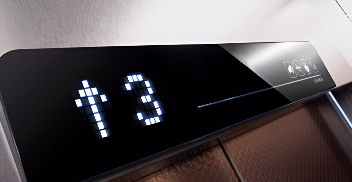 Крупний план електронного дисплея в ліфті, що показує стрілку вгору та цифру '3', що ймовірно вказує на рух ліфта вгору та поточний поверх.