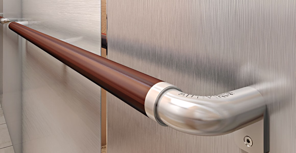 Крупний план дерев'яного поручня ліфта з металевими кріпленнями, прикріпленого до вертикальної панелі з текстурованою поверхнею.